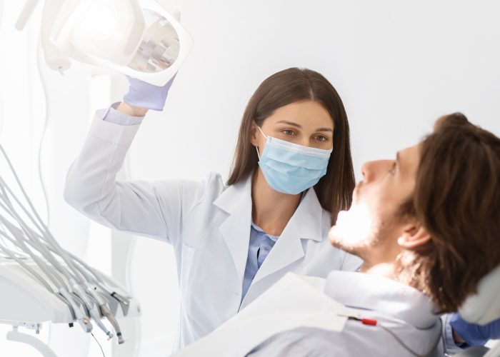 Dentist in mask turning on lamp before making check up